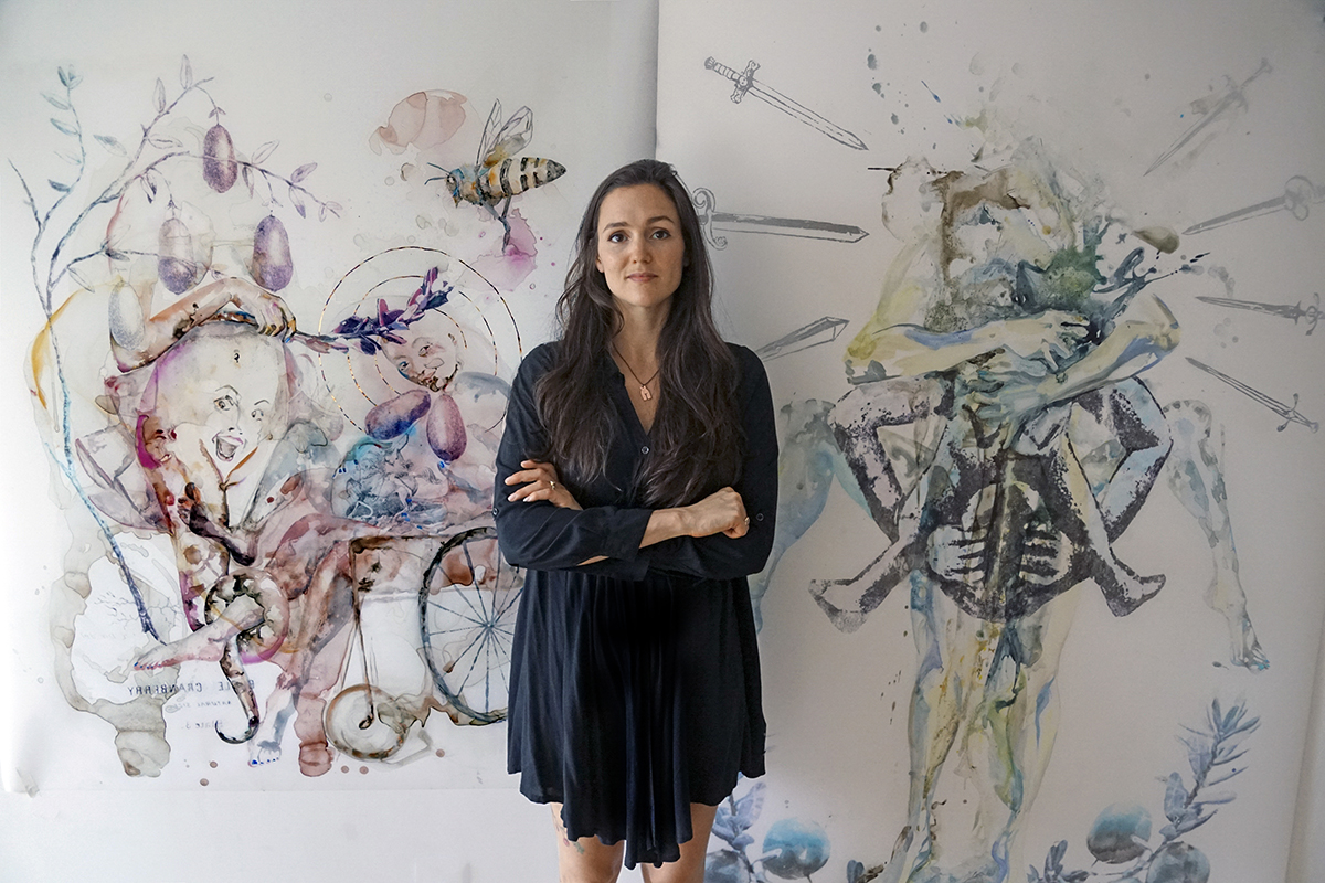 Alexandra Carter poses in front of two of her paintings