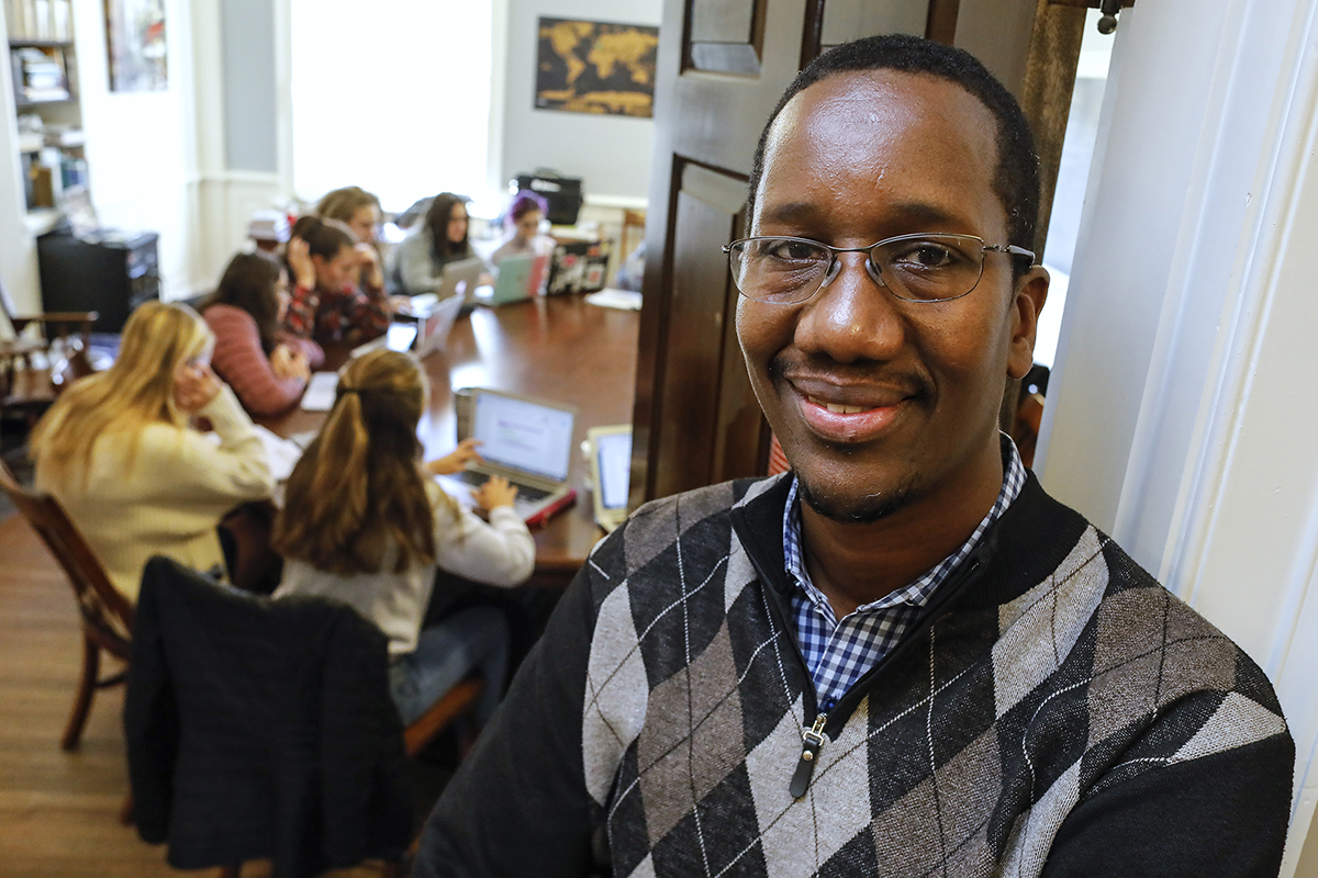 Amadou standing next to a Senegalese painting in his classroom.