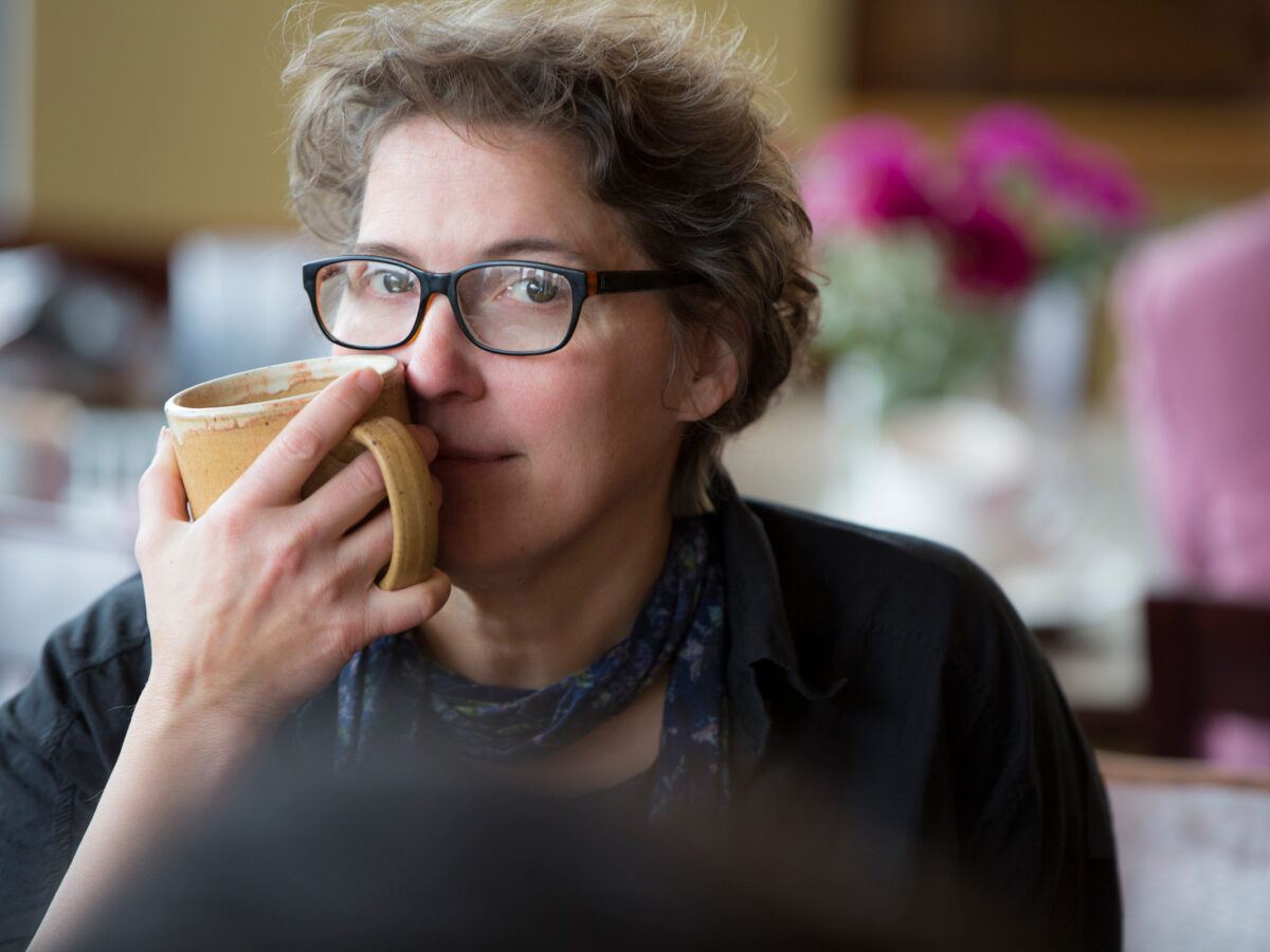 Shea holding a coffee mug close to her face.