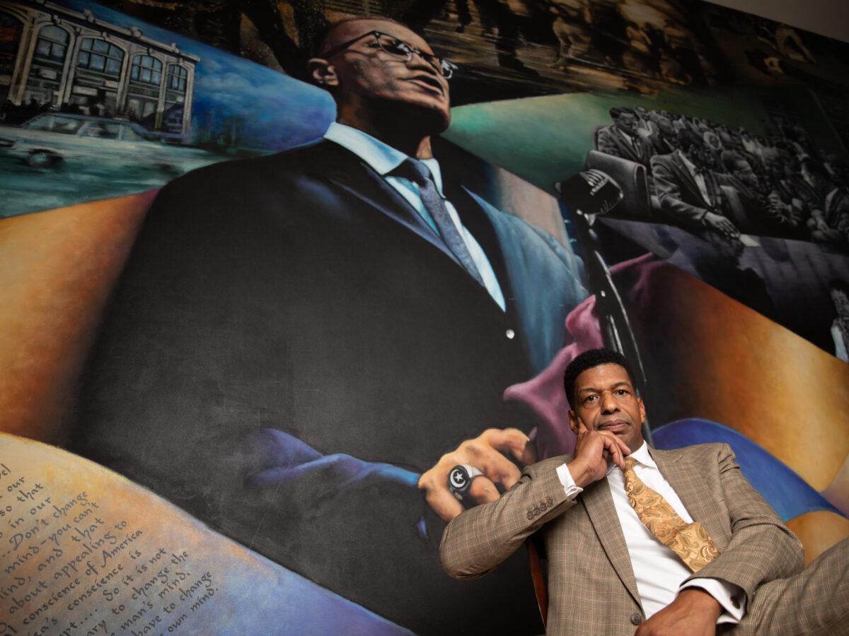 Julio Peterson sits in front of a mural.