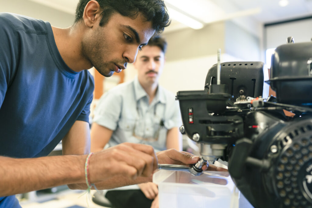 Student uses wrench to work on robot.