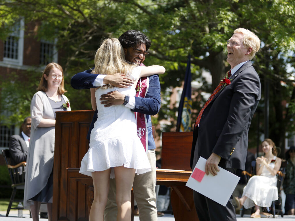 Two students embrace in a hug on the graduation stage