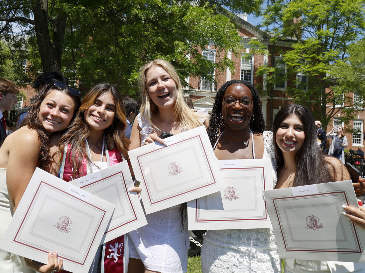 Group of students pose with diplomas at graduation