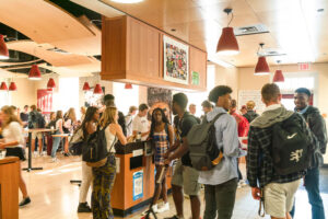 Students standing and hanging out during a busy time at Grill