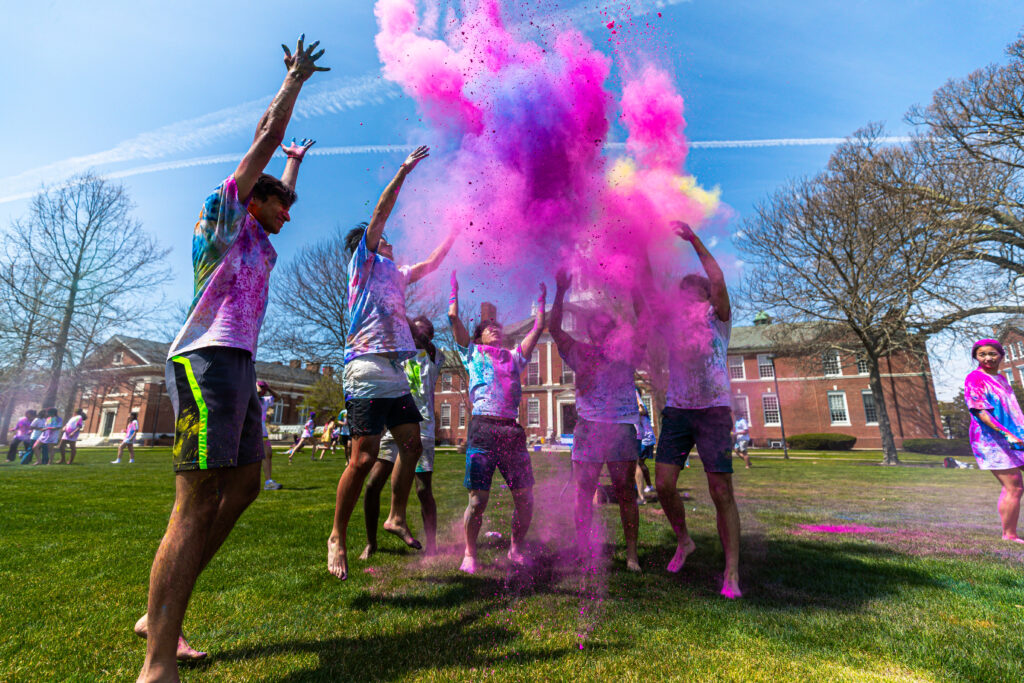 students celebrate Holi by throwing pink colored chalk and jumping