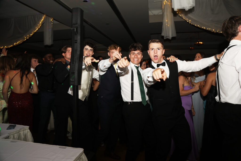 Two boys point at camera while attending prom.