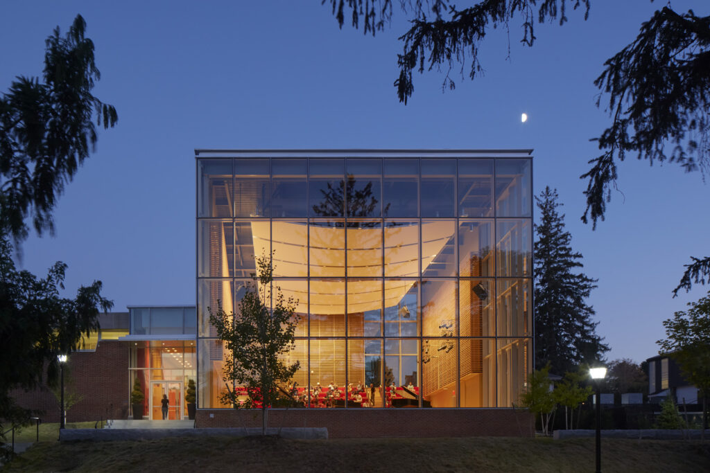 Large glass windows lit up at night at The Bowld