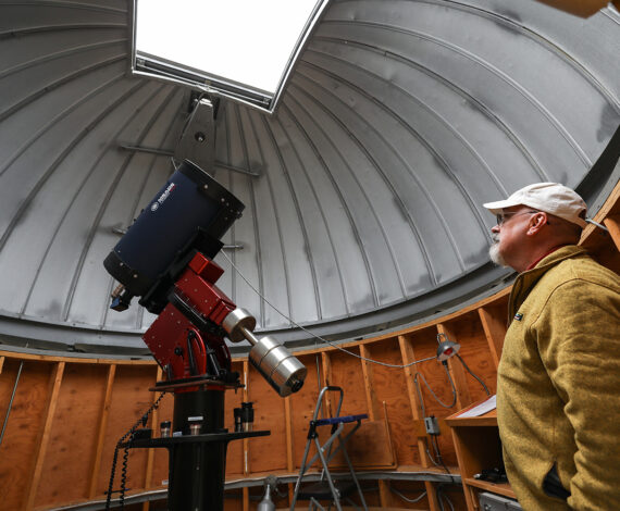 Professor John Blackwell stands next to telescope in the Grainger Observatory