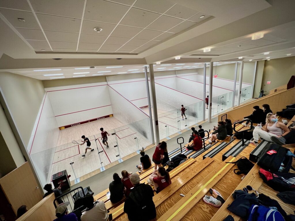 Wooden stands looking down at two athletes playing squash