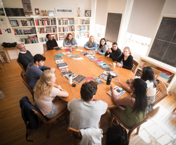 Harkness table full of students with books in the center