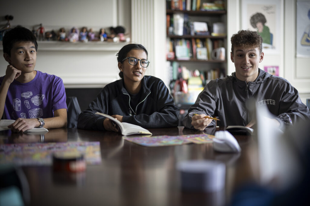 Three students in discussion around a Harkness table