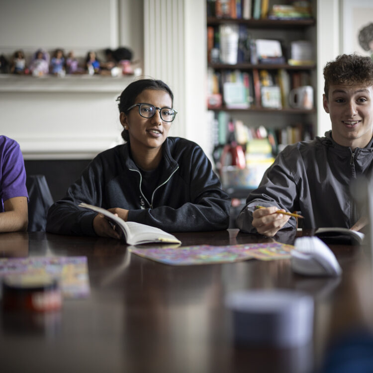 Three students in discussion around a Harkness table