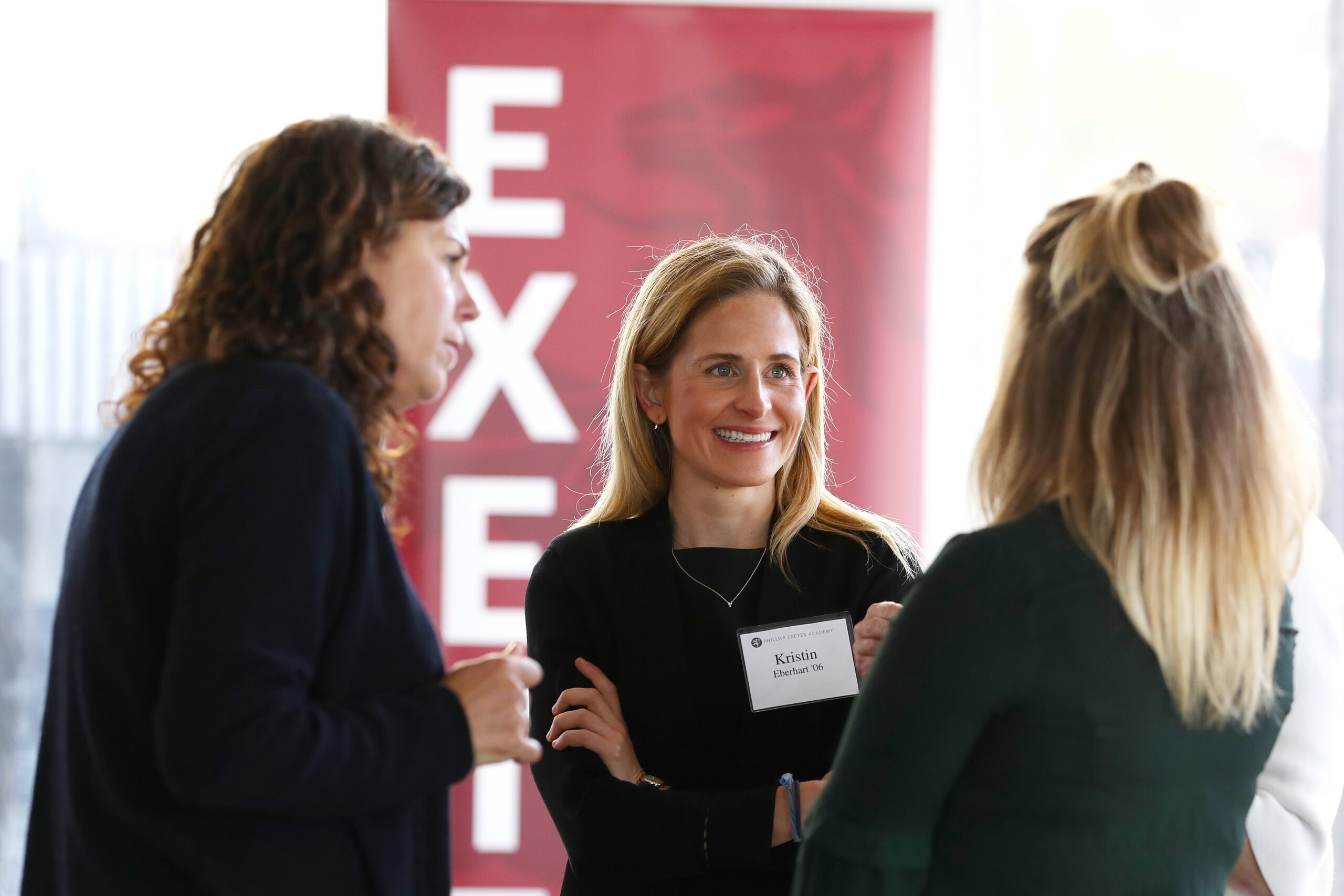 Three women stand together talking