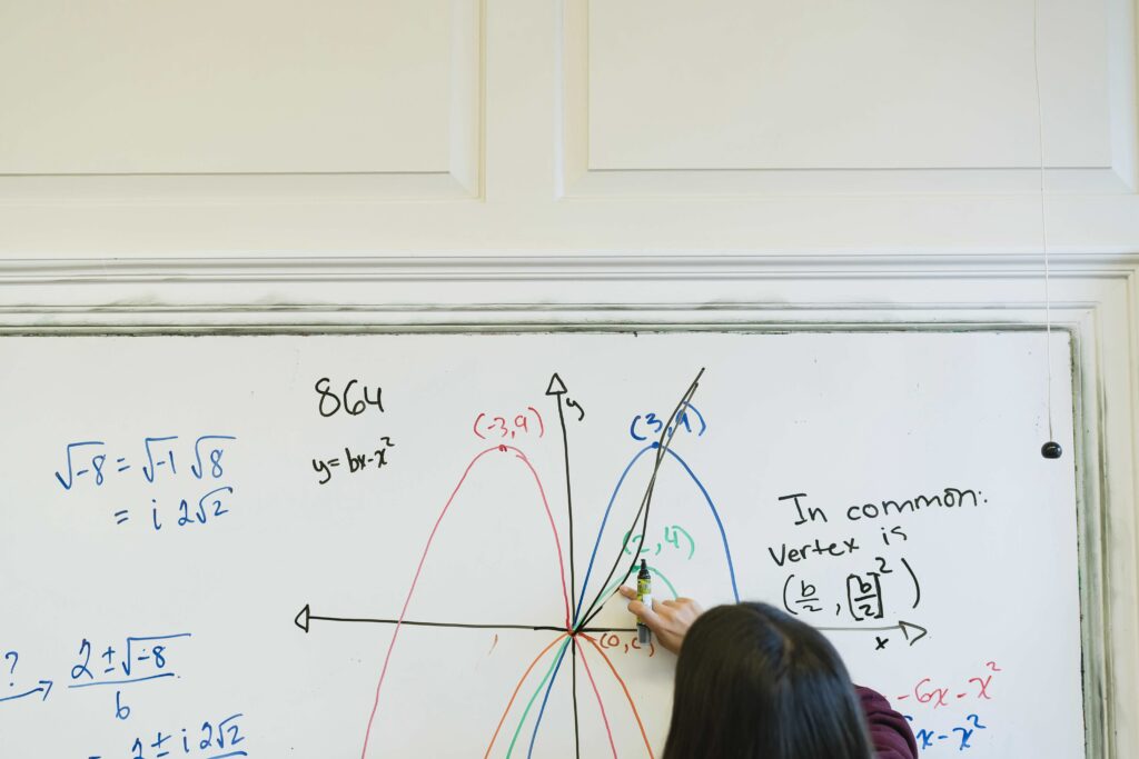 Students works on math problem at a whiteboard