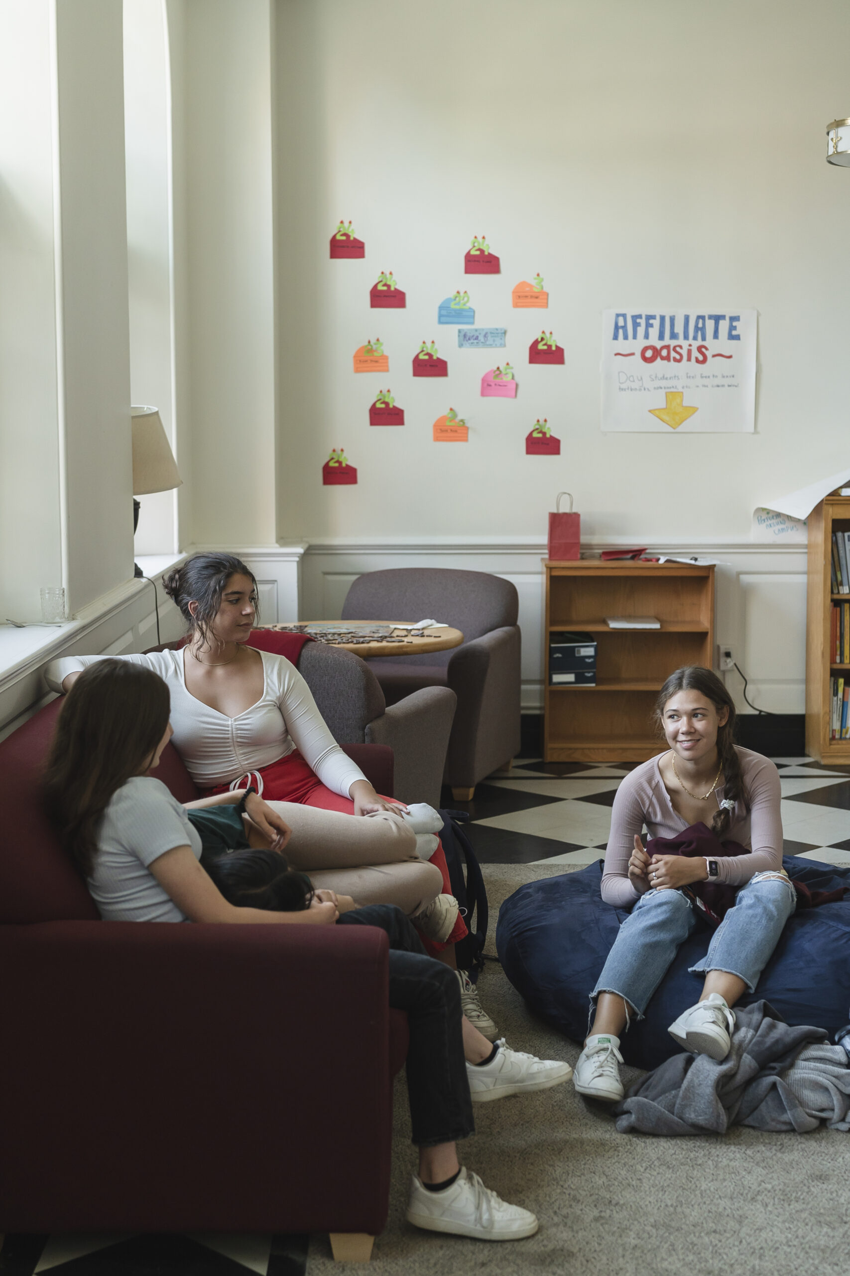 Three girls sit in common area in dorm