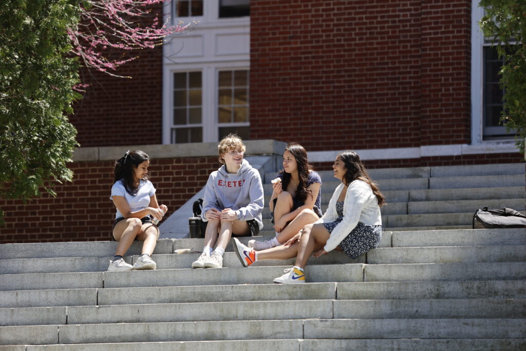 Four students sit on Academy Building steps