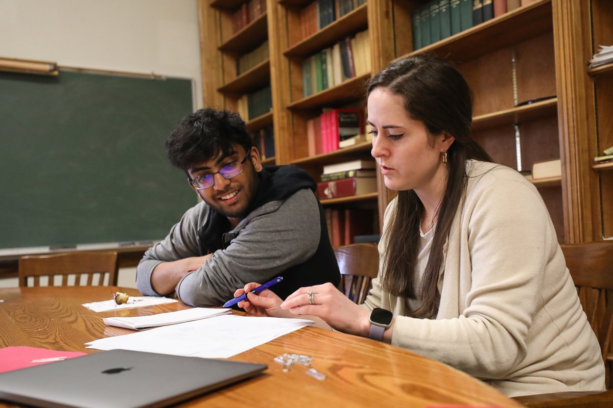 Teacher sits with student reviewing papers