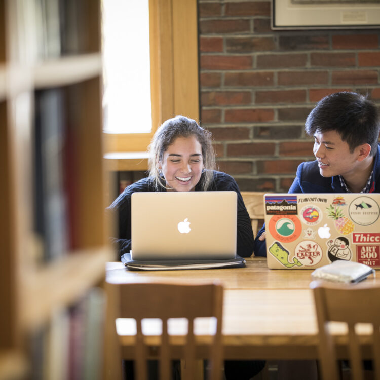 Students sit at table with laptops