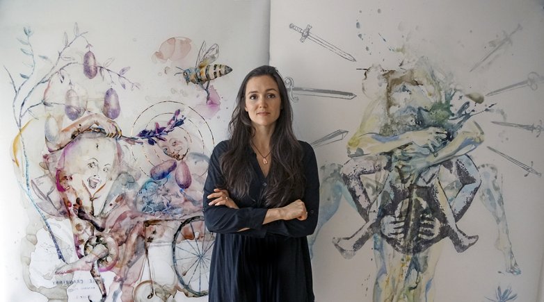 Alexandra Carter poses in front of two of her paintings