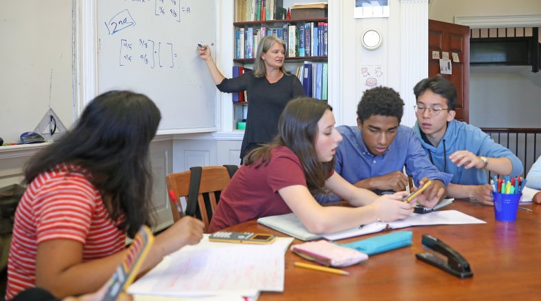 Students work on a math problem together around a Harkness table.