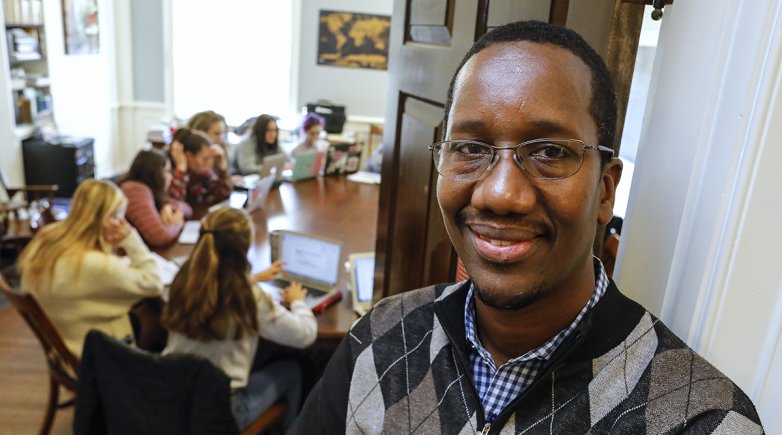 Amadou standing next to a Senegalese painting in his classroom.