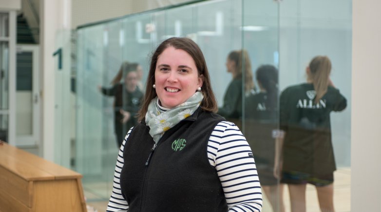 Coach Sarah Odell standing in front of squash courts at Exeter