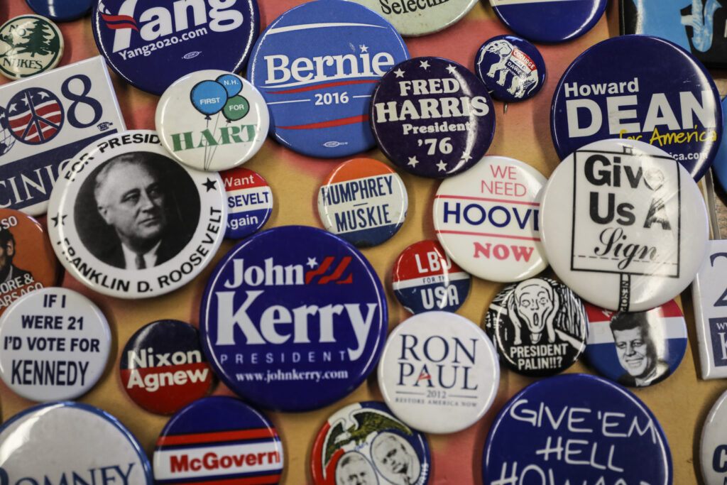 Variety of colorful political pins hang on cork board.