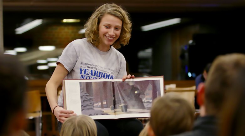 Grace Gray reads from a book to a group of children in the library.