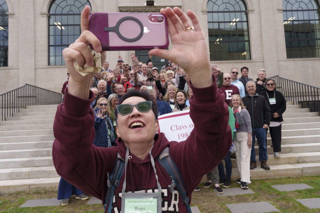 Man stands taking a selfie in front of large group