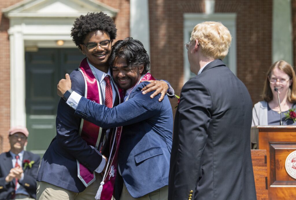 Two students hug on graduation stage