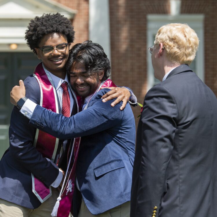 Two students hug on graduation stage