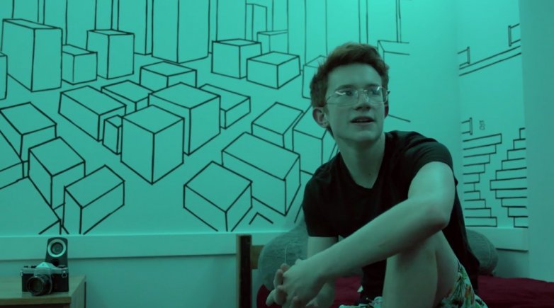 Ben Harrison sits in front of his decorated dorm room wall