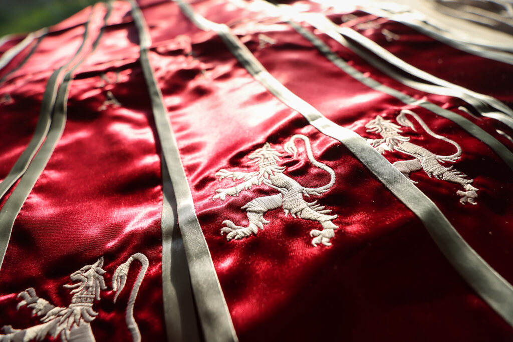 Close up of red graduation stoles with white lion rampant