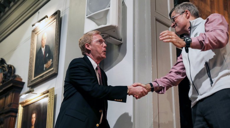 Bill Rawson shakes hands with Trustee Tony Downer in Exeter's Assembly Hall.