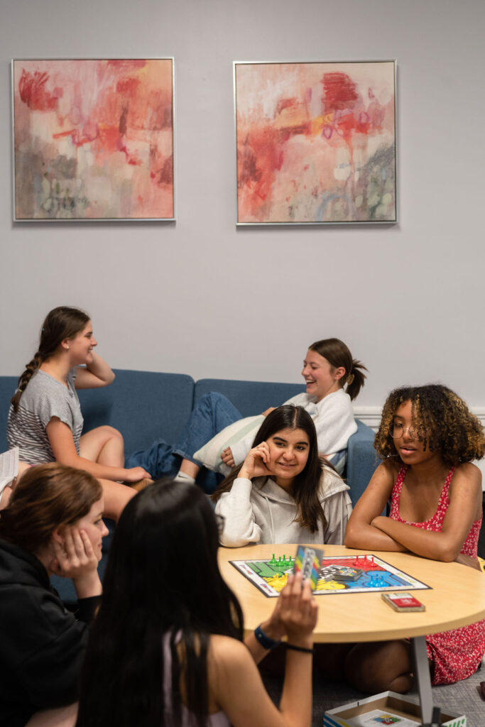 Group of girls sit in dorm common area and play board games