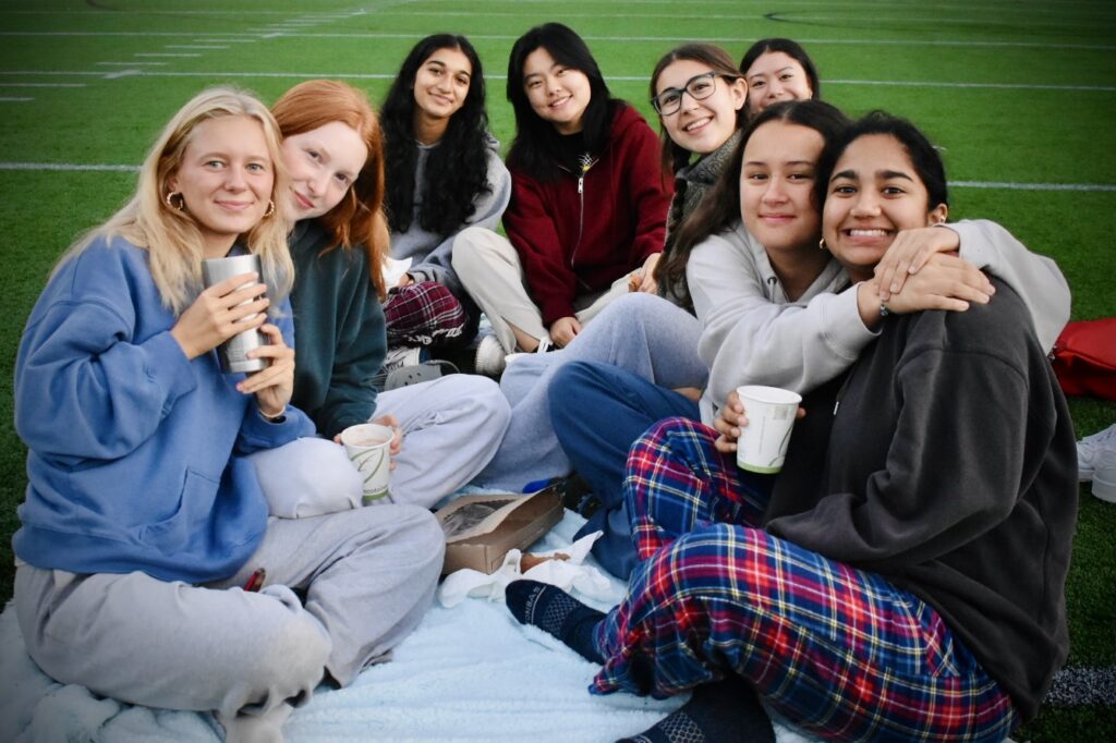 Group of girls sit on picnic blanket