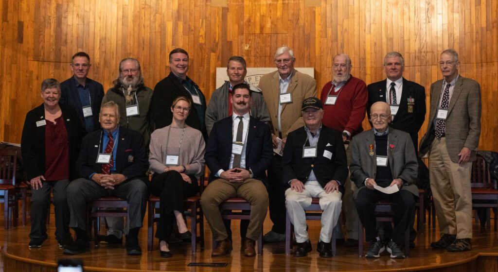 Full panel of guests for Exeter Salutes poses for photo on Assembly Hall stage.