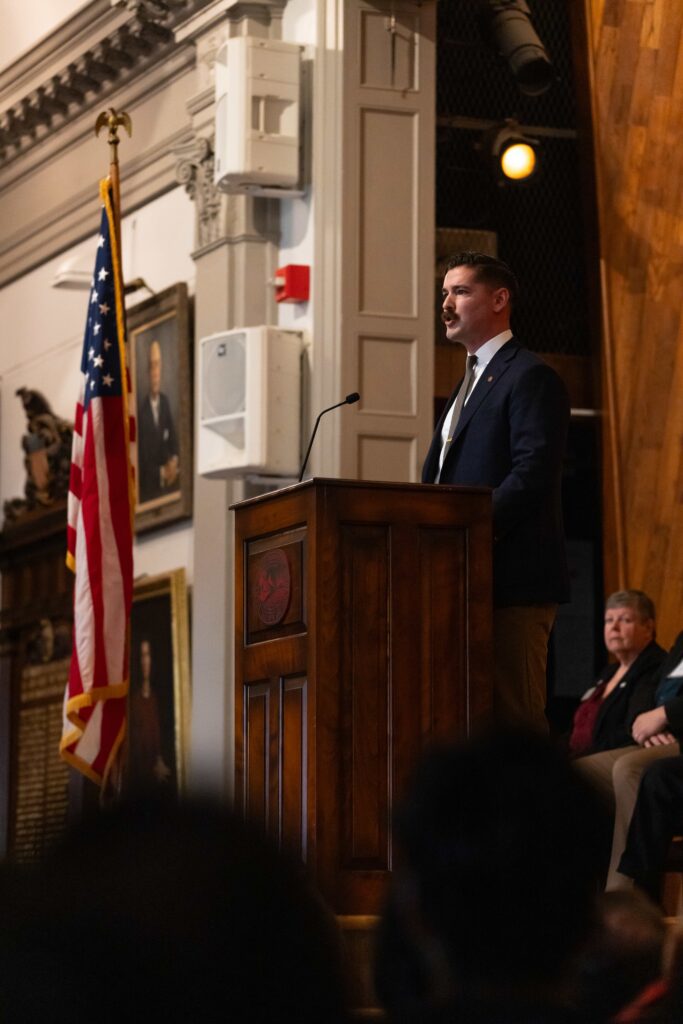 Caleb Hoffman Johnson stands at podium while delivering speech.