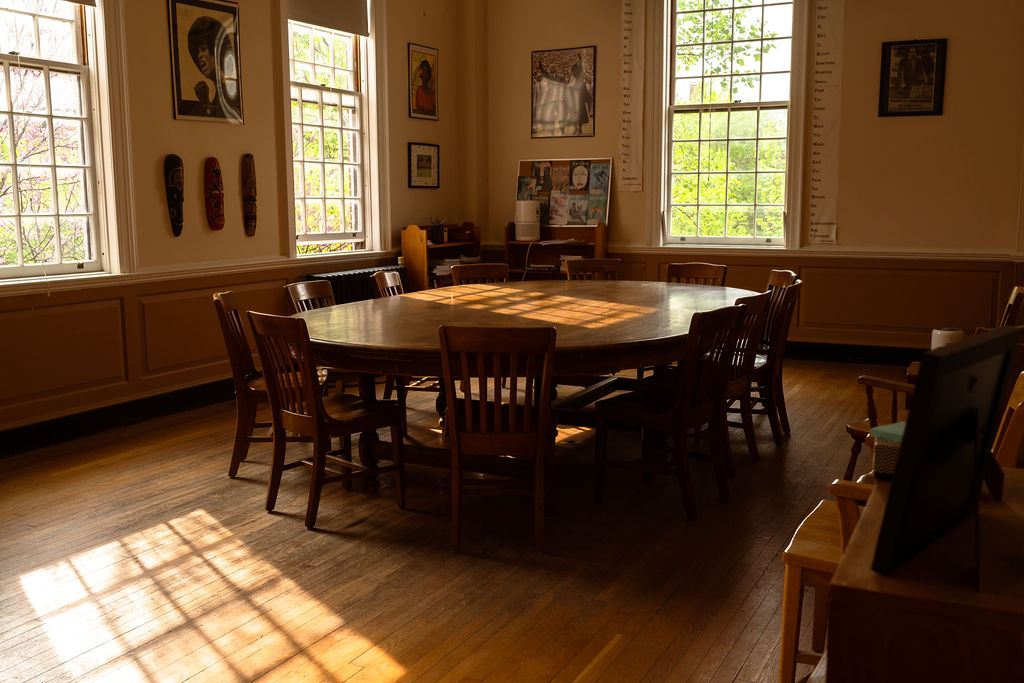 Sunlit room with an empty Harkness table at the center