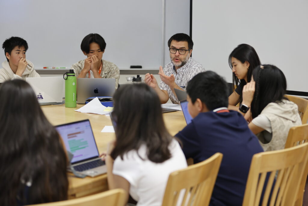 Teacher and students sit around Harkness table.