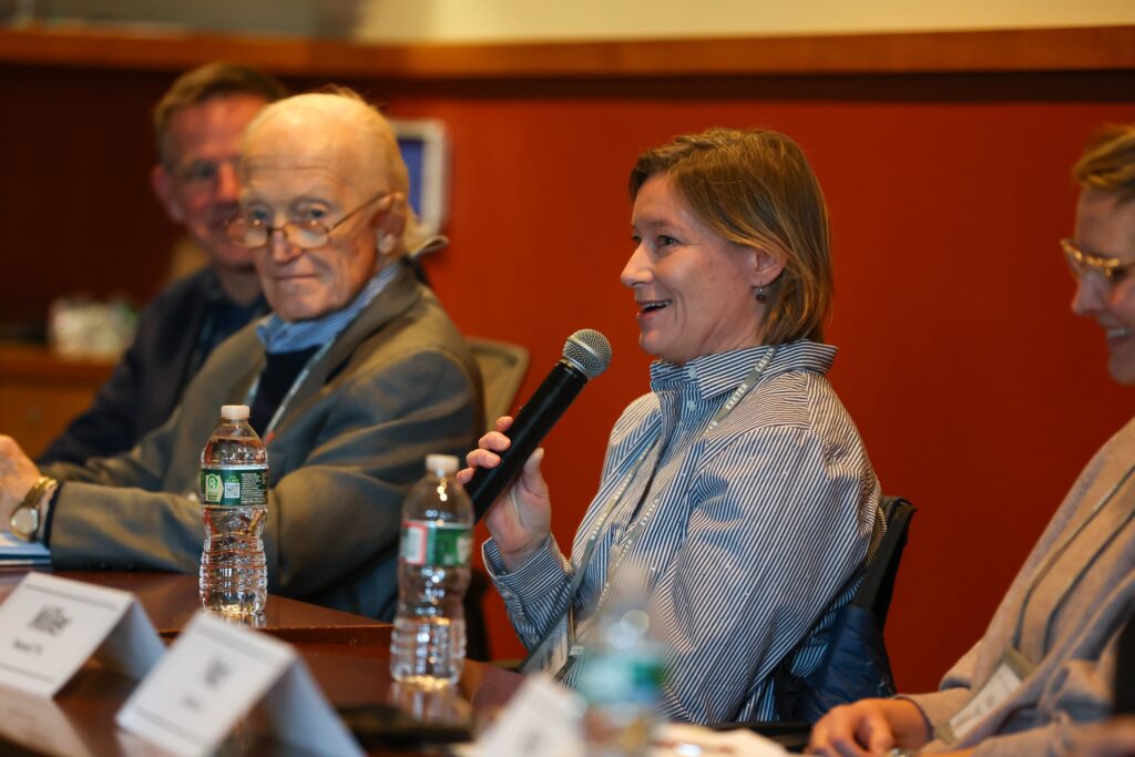 Panel speaker talks to crowd with a smile.