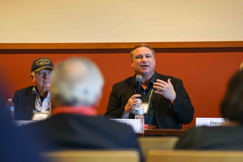 Panel speaker holds microphone and talks to crowd.