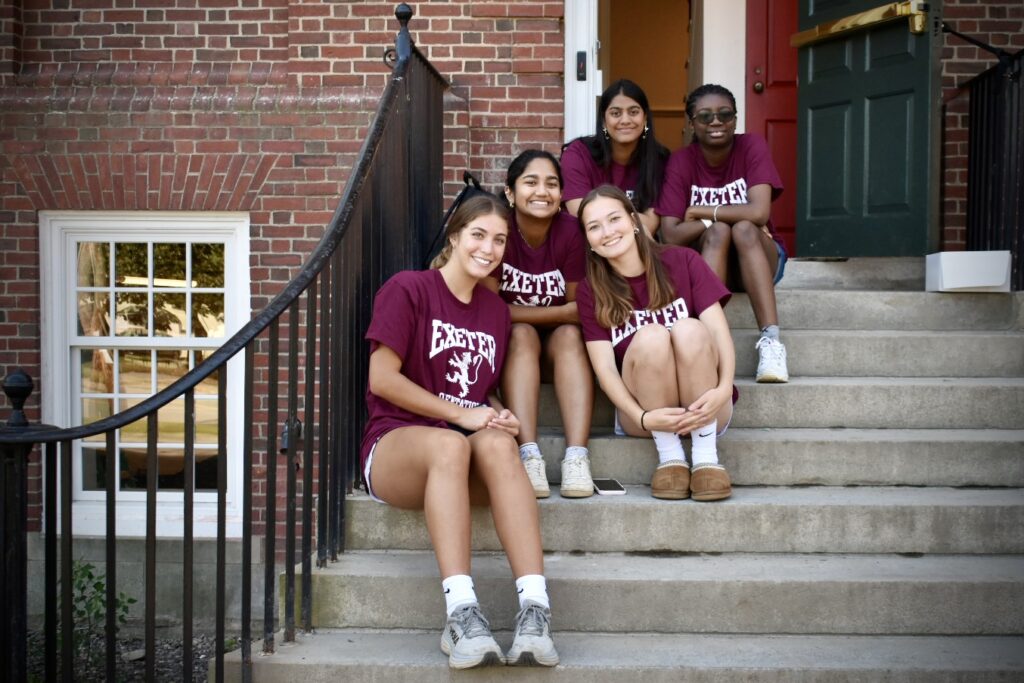 Group of girls sitting on the stairs outside their dorm.