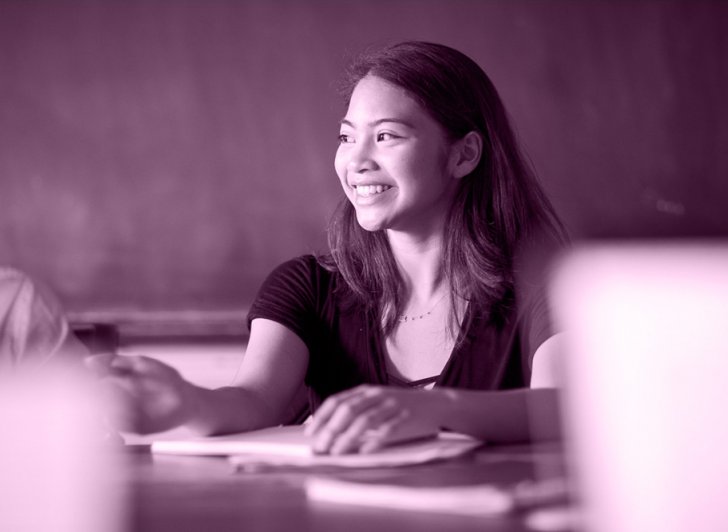 Exeter student seated at a Harkness table and smiling