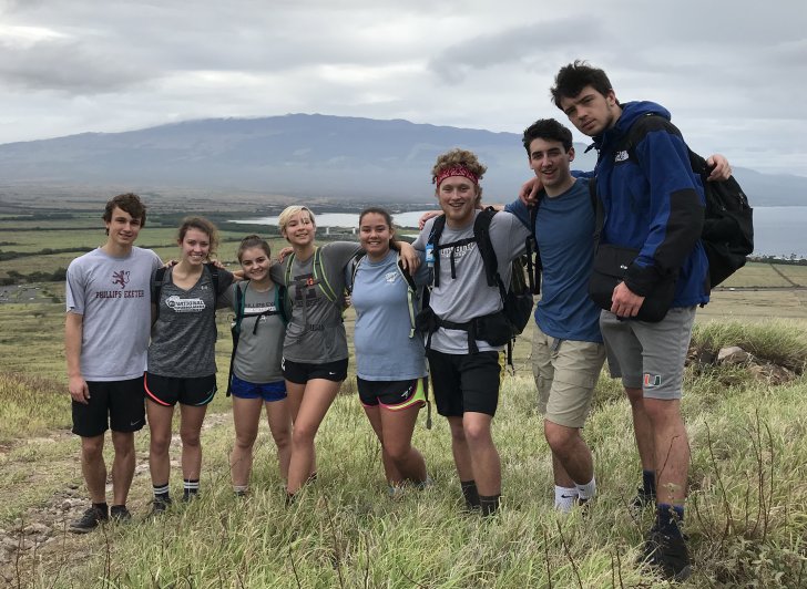 A group of Exeter students standing in front of the ocean in Maui