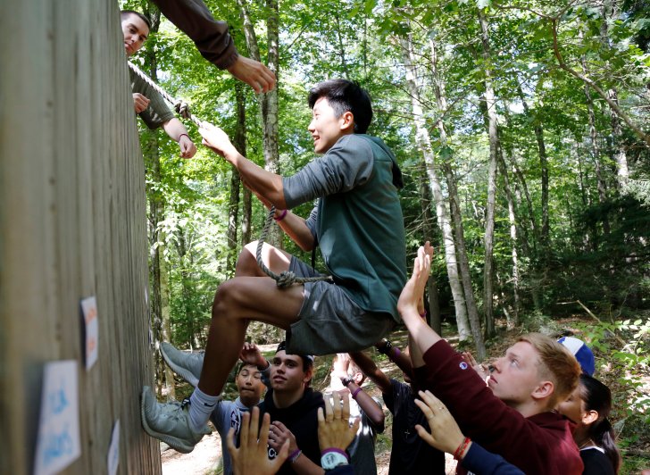 Members of the class of 2023 work together to overcome an obstacle during orientation activities at Brown Center