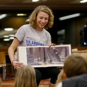 Grace Gray reads from a book to a group of children in the library.