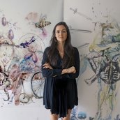 Alexandra Carter poses in front of two of her paintings