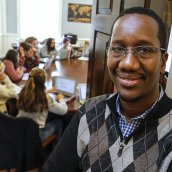 Amadou standing next to a Senegalese painting in his classroom.