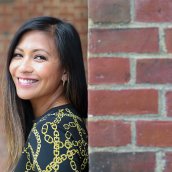 Sherry Hernandez leaning against a brick wall and smiling